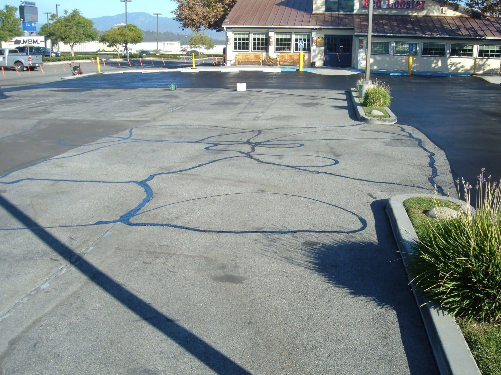 Gray asphalt lot with a web of freshly filled cracks, ready for sealcoating