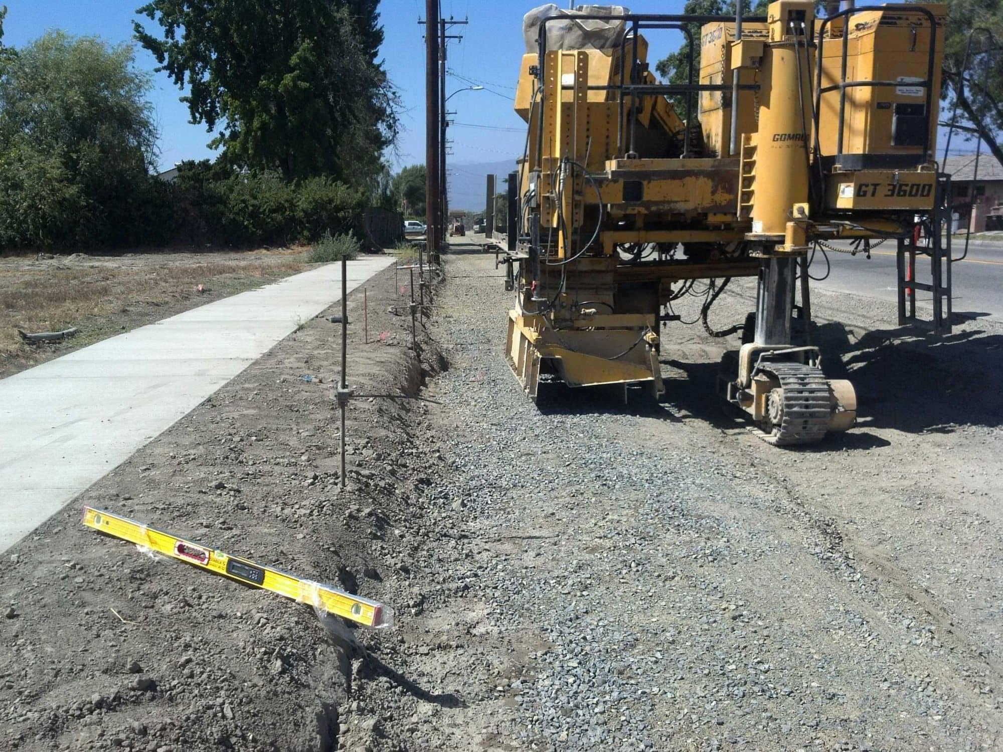 Curb machine shaping a new curb line beside a freshly placed sidewalk