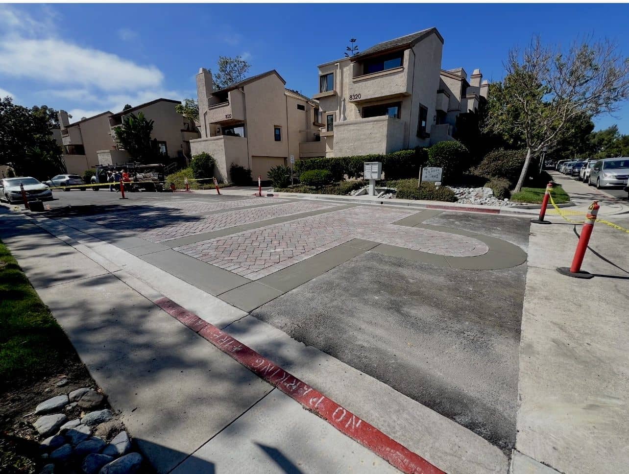 Decorative brick-pattern entry framed by new concrete borders at a townhome community