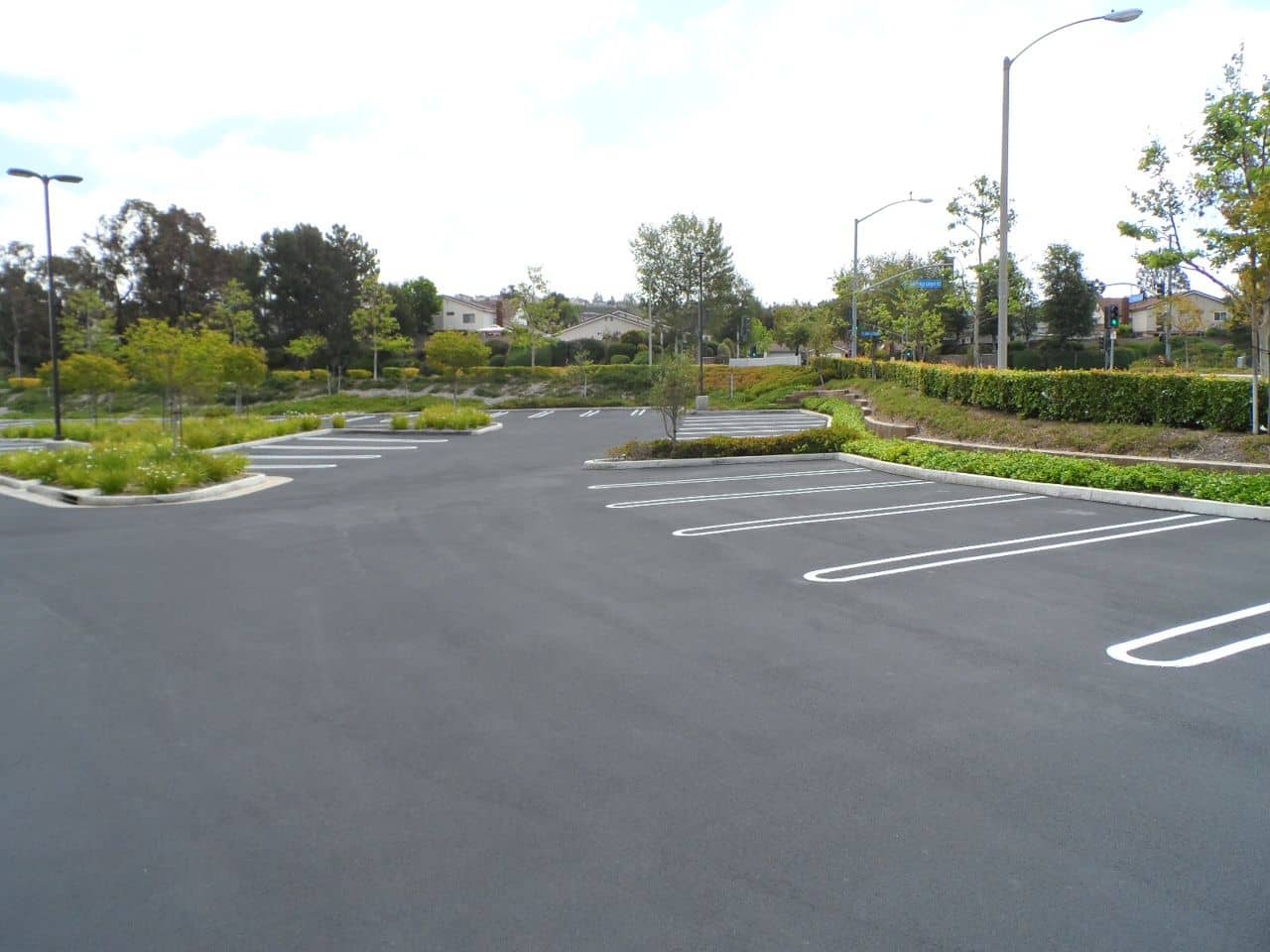Freshly sealed parking lot with bright white stall lines and landscaped medians