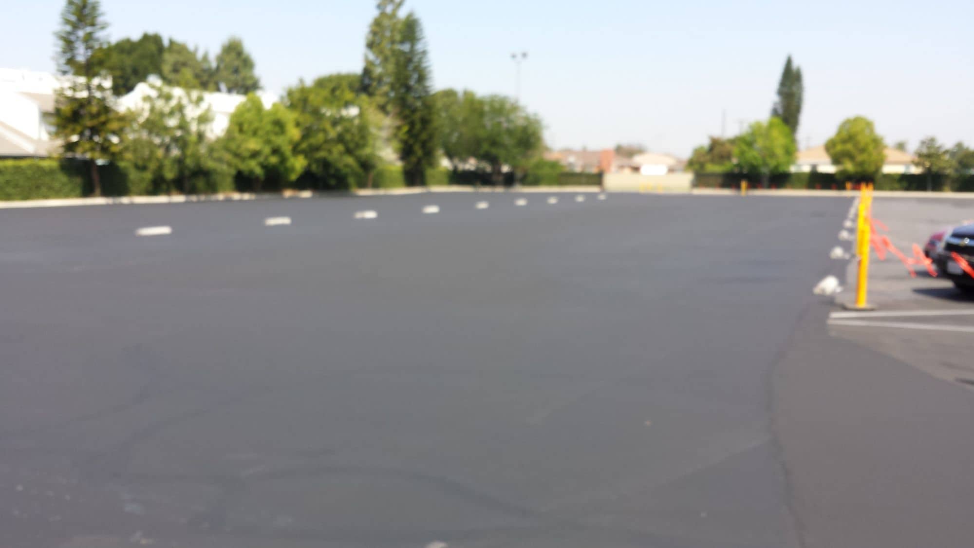 Wide view of a large lot after sealcoating, with a uniform deep-black surface