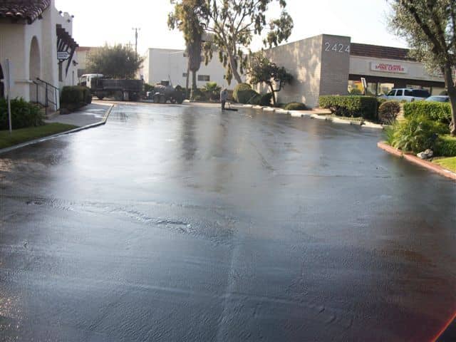 Glossy newly sealed driveway leading toward a commercial building