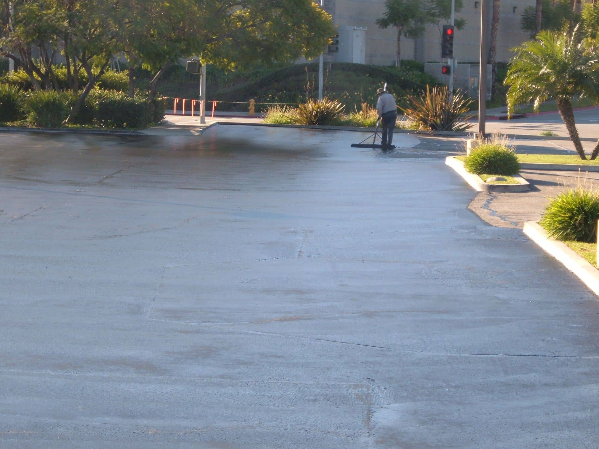 Wet, freshly sealed drive aisle shining between landscaped planters