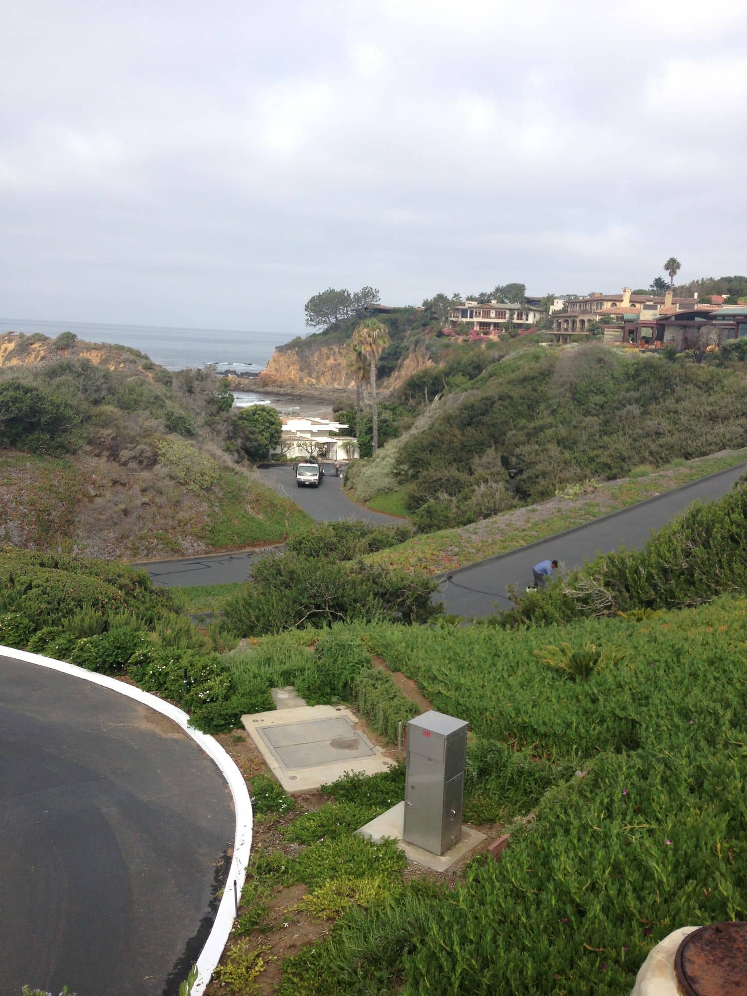Before: overlook of the narrow access drive winding down a coastal hillside, prior to sealing