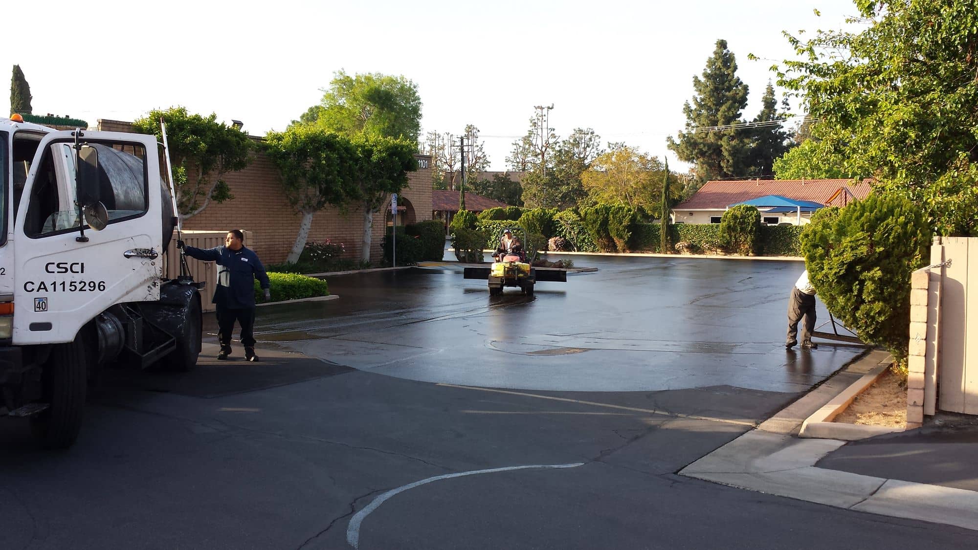 Freshly sealed lot gleaming in early light with the crew's truck parked at the edge