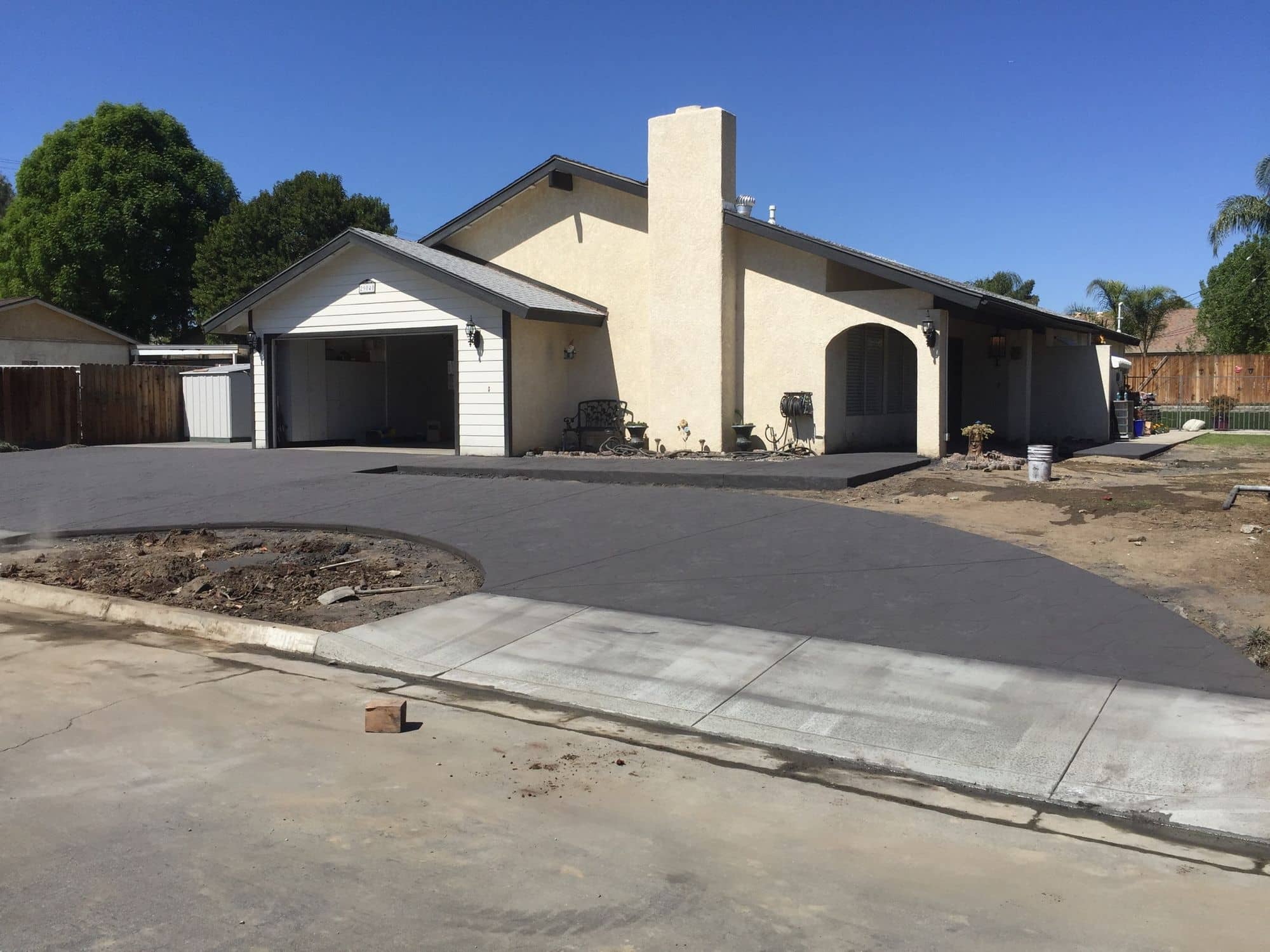 Newly paved asphalt driveway leading up to a single-story stucco home