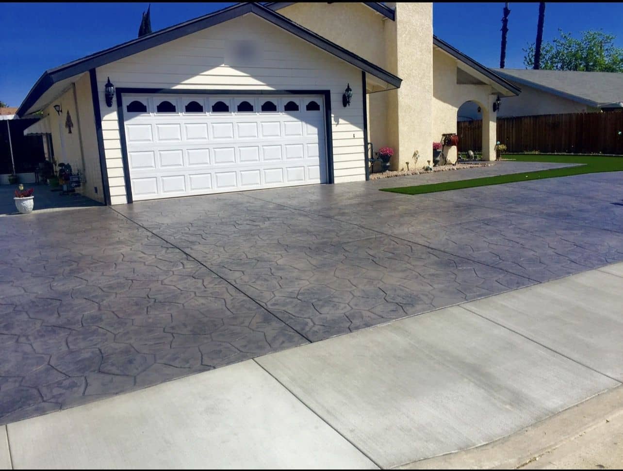 Gray stamped-concrete driveway with a stone pattern in front of a single-story home