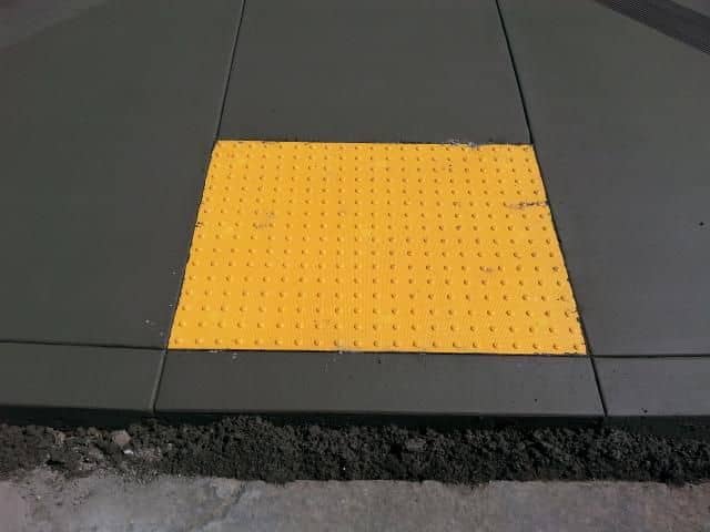 Yellow truncated-dome detectable warning panel set into a new concrete curb ramp